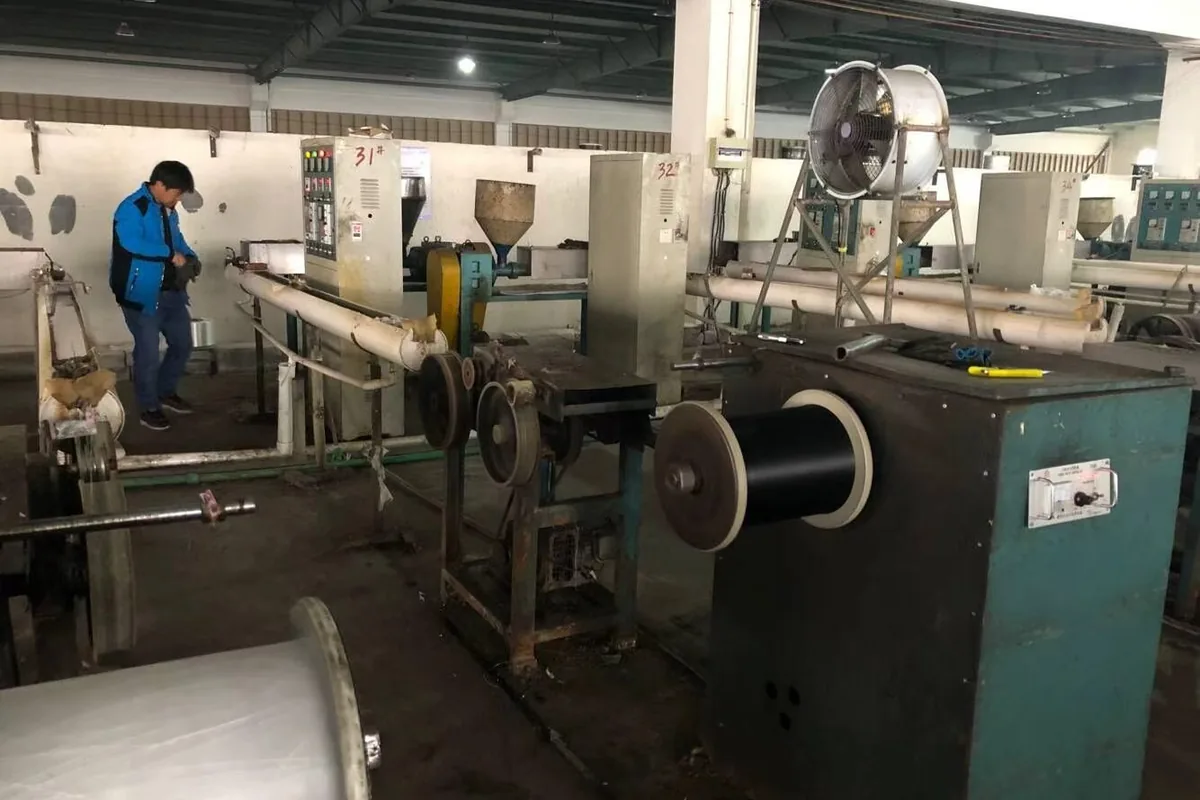 Yarn extrusion and coating line at the woven vinyl production base in Zhejiang: pellets fed to the extruder, yarn coated and wound onto a bobbin