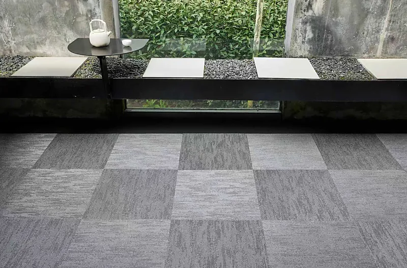 Acoustic modular carpet tiles in woven vinyl, laid in a two-tone checkerboard in a lounge