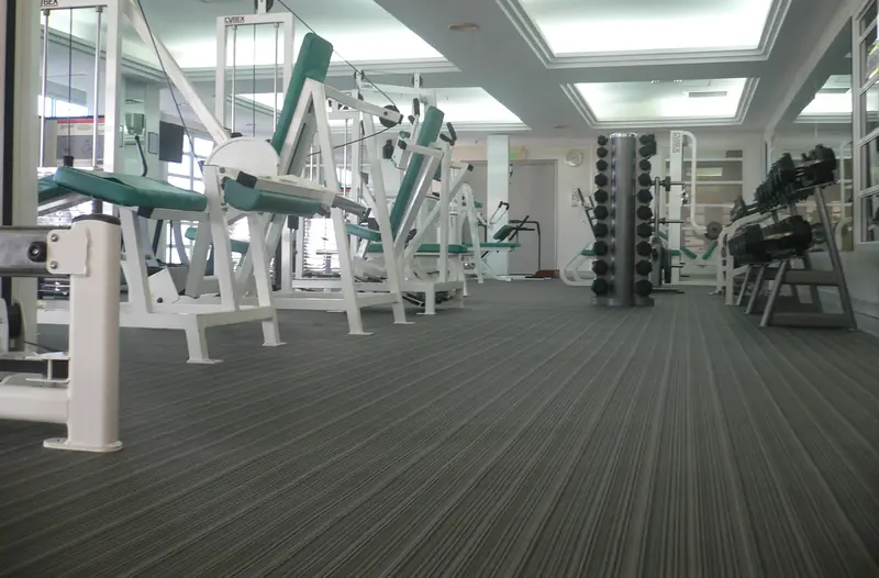 Strength machines on a woven vinyl floor in a gym